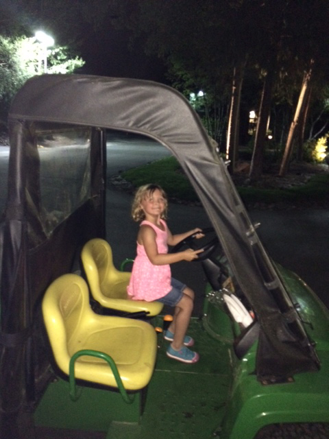 A young girl posing in a golf cart