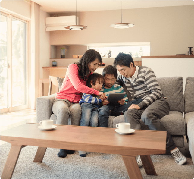 A family sitting on a couch and looking at an iPad in their great room 