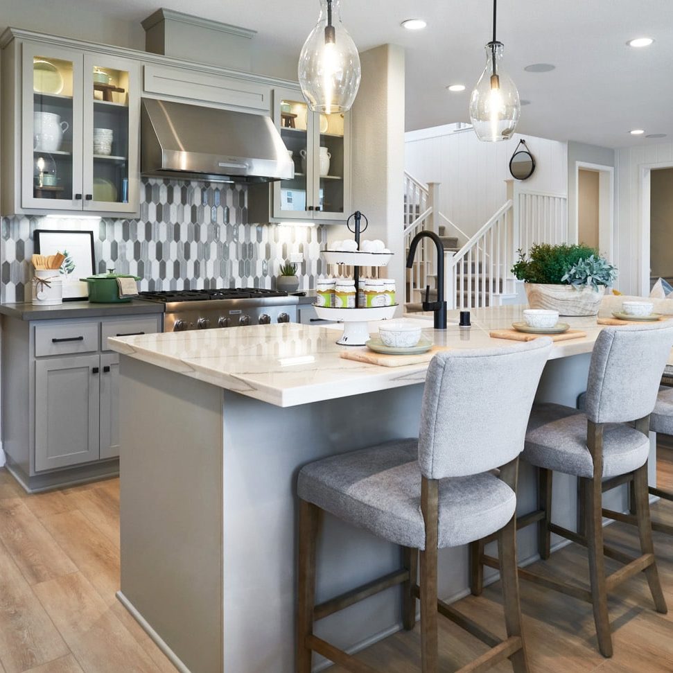 A kitchen with gray cabinets and light countertops