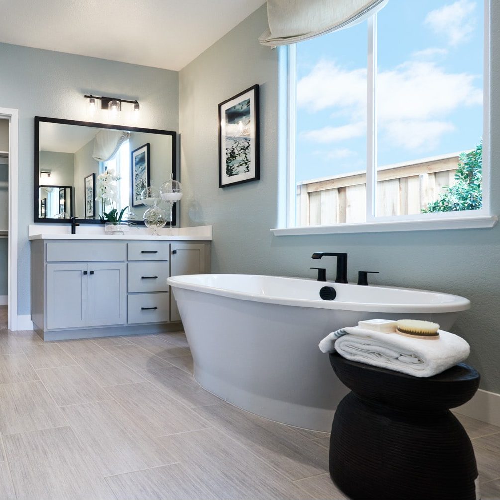 A master bathroom with a large soaking tub and a gray vanity