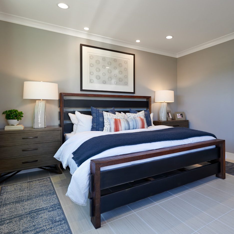 A master bedroom with a dark wood bed frame and white and blue bedding